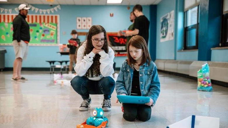 College student helps elementary school student with robot